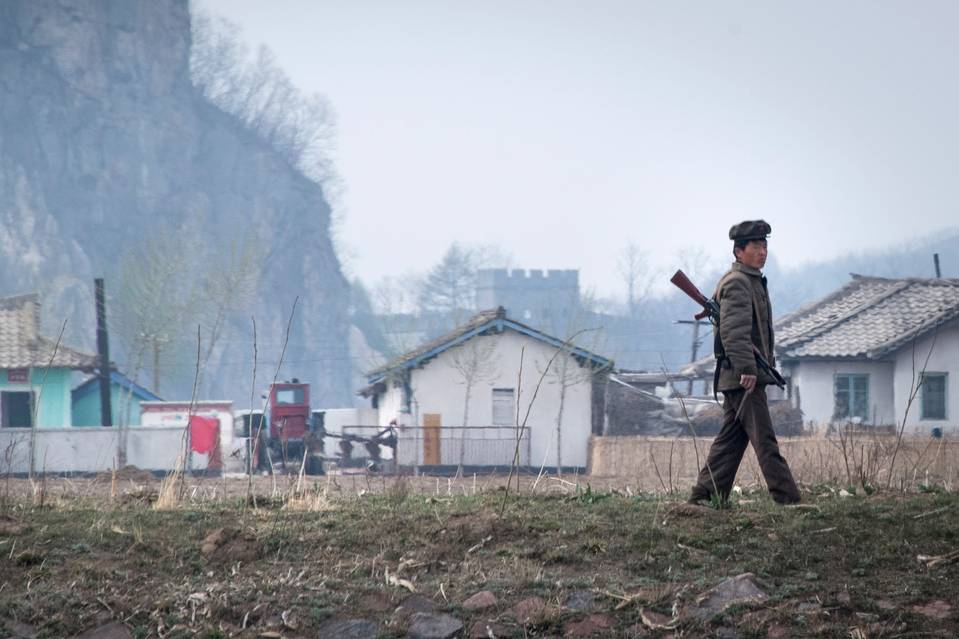 一名朝鲜士兵在新义州附近的鸭绿江附近行走，对面是中国边境城市丹东。照片摄于4月份。