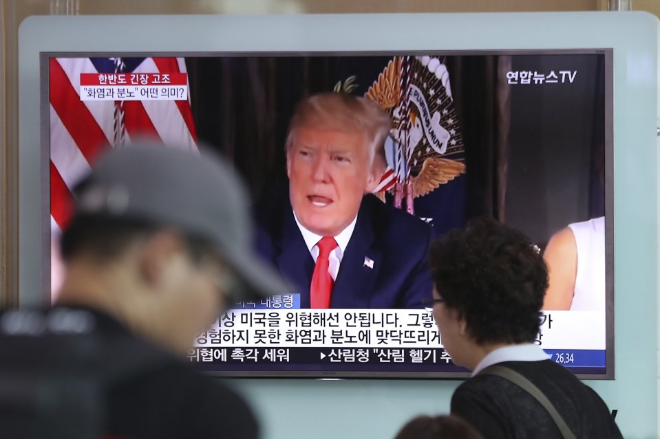 周三，人们从首尔火车站的一块正在播放当地新闻节目的电视屏幕前走过，屏幕上显示了特朗普头像。 