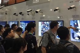 参观人群在浙江大华技术股份有限公的展台观看装备人脸识别技术的摄像机的技术展示。