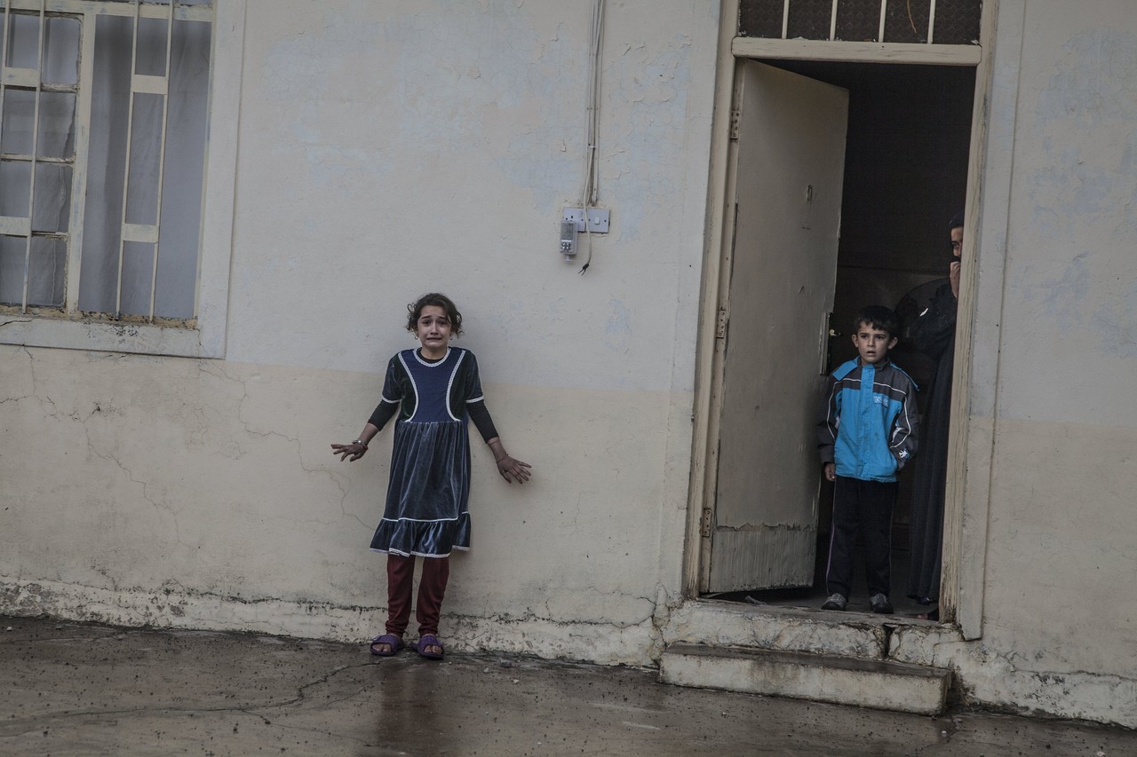 在摩苏尔东部的Gogjali区，一个女孩站在家门外。伊拉克特种作战部队的成员正在她家中进行搜查，以确认是否藏有伊斯兰国(ISIS)成员或其装备。